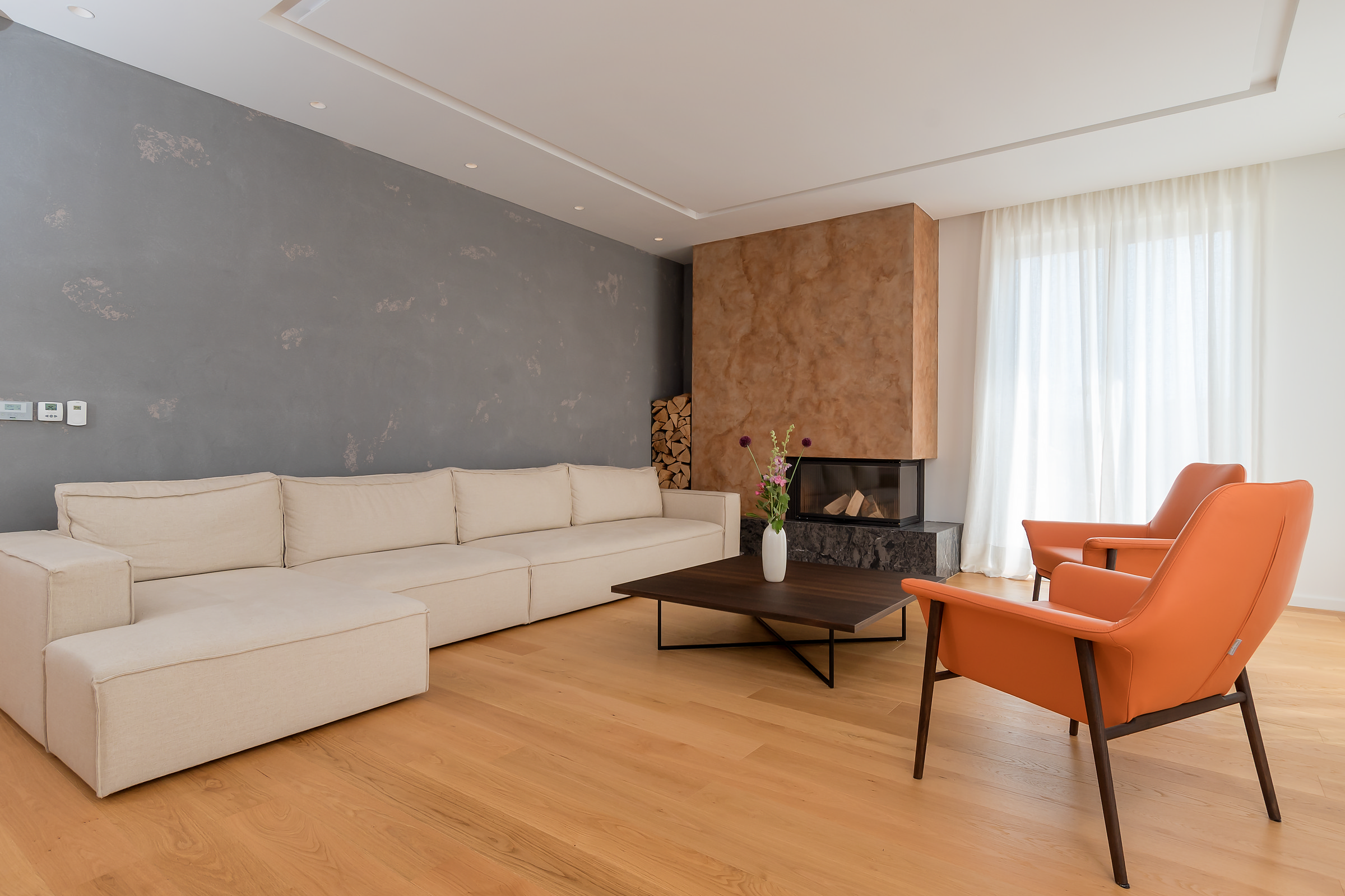 Living room with fireplace, cream sectional sofa and orange leather chair