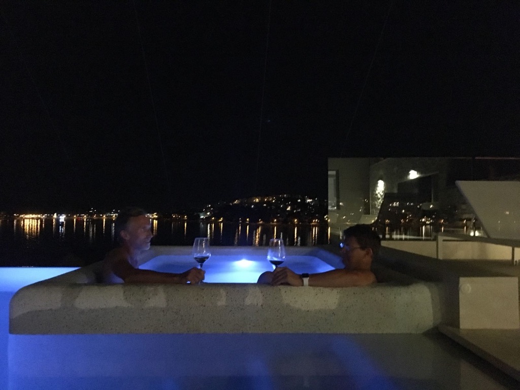 Two friends enjoying wine in the jacuzzi at night